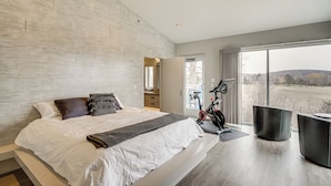 Un dormitorio moderno con una cama grande, una bicicleta y vistas al exterior.