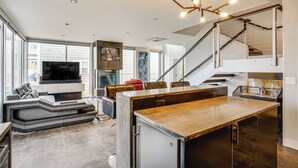 Cocina moderna con una isla central, refrigerador empotrado y una zona de comedor con banco.