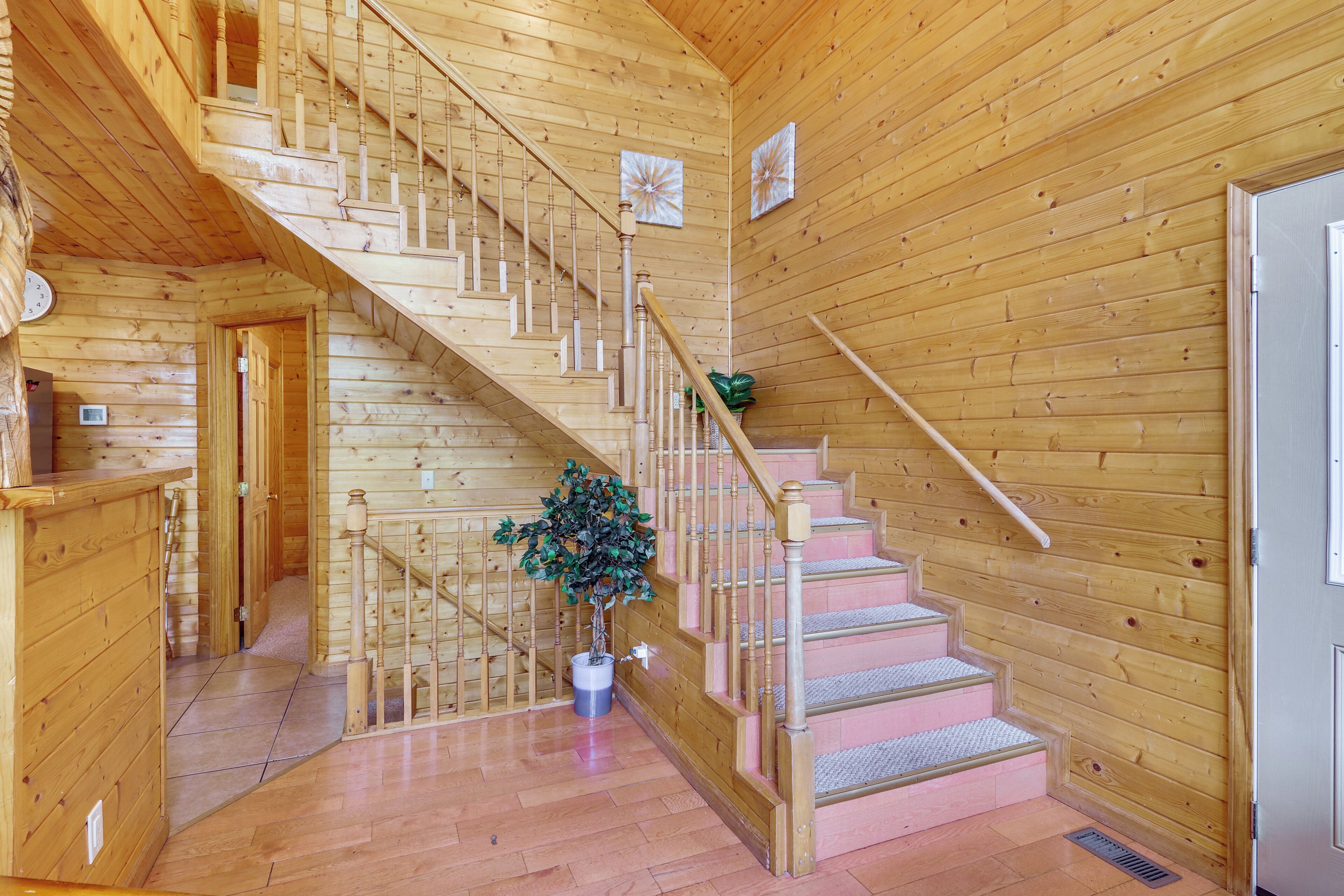 A wooden staircase with a handrail, a potted plant, and a door on the right.