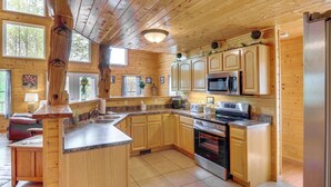 Cocina estilo cabaña de madera con encimera de granito, electrodomésticos de acero inoxidable y ventanas amplias.