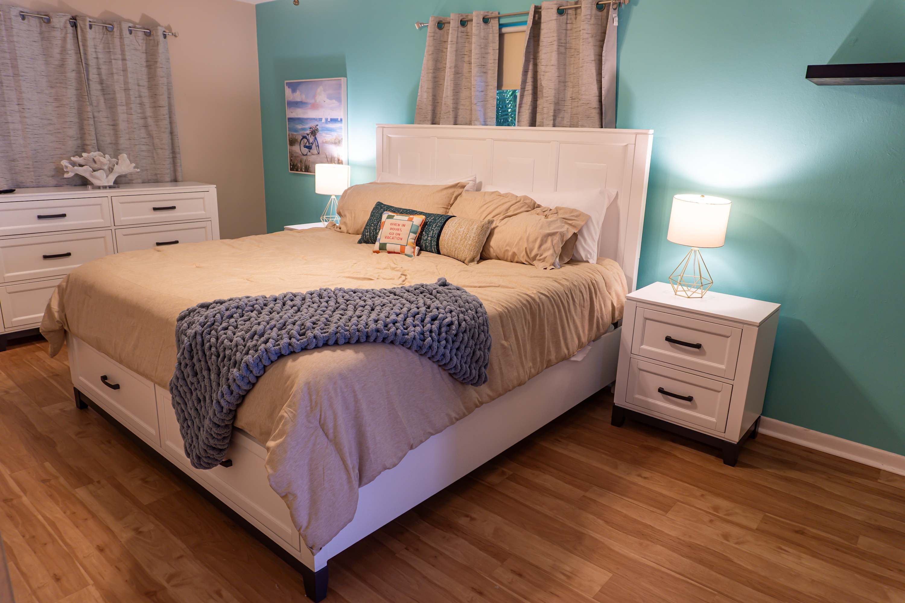 Een slaapkamer met een bed, nachtkastjes en een dressoir.