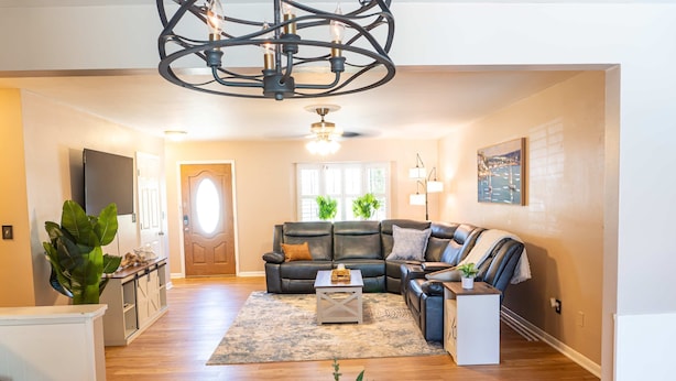 A spacious living room with a large sectional sofa, a coffee table, and a chandelier. - Four Bed Home With Pool Game Room Bar Near Beach (Largo)
