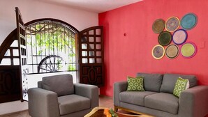 Una sala de estar con dos sofás grises, una mesa de centro de madera y una pared roja decorada con detalles circulares.