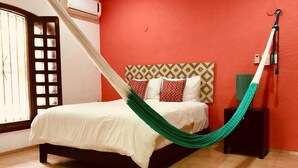 Una cama con una hamaca verde, un cabecero estampado y una pared roja.