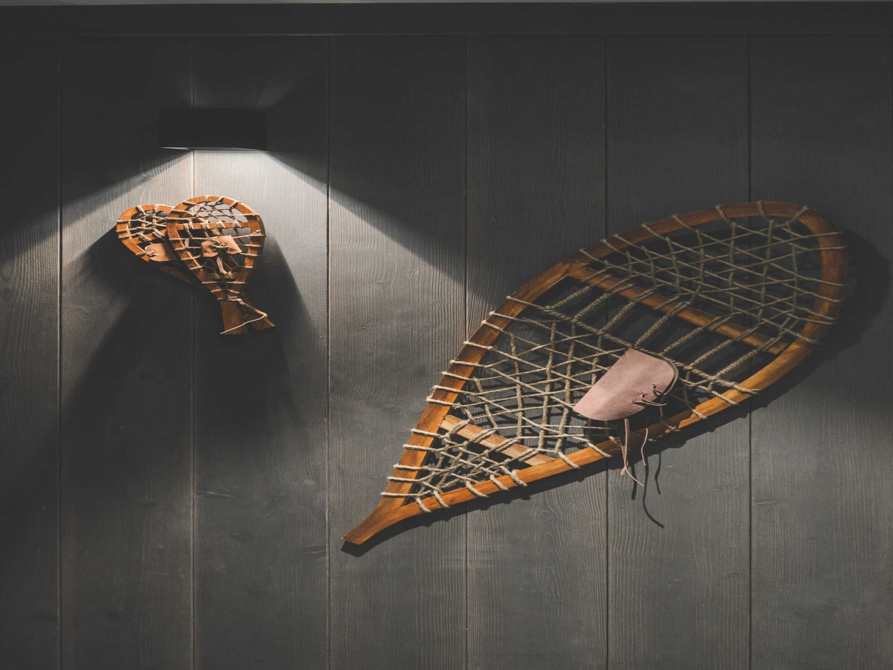 Two wooden boats with intricate lattice designs, mounted on a dark wooden wall.