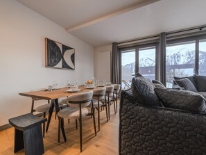 A modern dining area with a wooden table, grey upholstered chairs, and a grey quilted sofa. - Apartment in Plan Peisey Near Vanoise Park (Peisey-Nancroix)