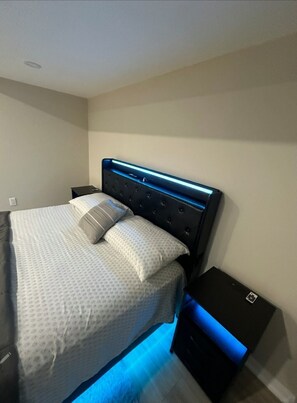 Un dormitorio moderno con cama, mesita de noche y cómoda.
