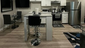 Una cocina moderna con armarios blancos, electrodomésticos de acero inoxidable y una isla central con taburetes de bar.