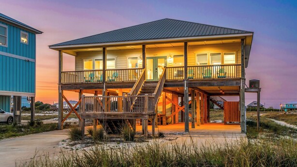 A two-story beachfront house with a balcony, a staircase, and a covered porch. - Gulf View Beach Retreat with Hot Tub (Gulf Shores)