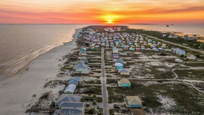 An aerial view of a coastal residential area with houses along the beachfront and a road leading through the community. - Gulf View Beach Retreat with Hot Tub (Gulf Shores)