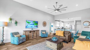 A spacious living room with a television, wooden flooring, and a ceiling fan. - Gulf View Beach Retreat with Hot Tub (Gulf Shores)
