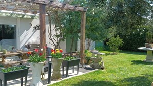 En uteplats med en träpergola, utomhusmöbler och planterade växter i krukor.