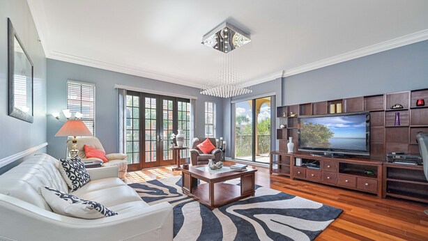 A spacious living room with a white sofa, a coffee table, and a TV on a wooden stand. - Luxurious Top Floor unit at The Residence at Coconut Point (Estero)