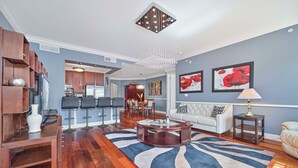 A modern living room with a wooden coffee table, a patterned rug, and a dining area with bar stools. - Luxurious Top Floor unit at The Residence at Coconut Point (Estero)