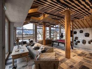 Una habitación acogedora con mesa de billar, un sofá y un cofre de madera.