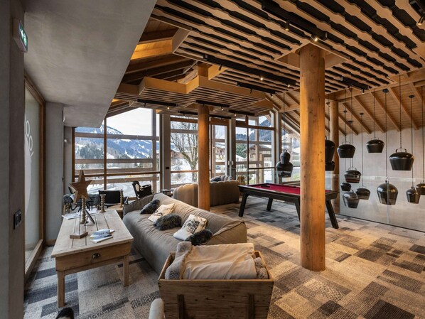 A cozy room with a pool table, a sofa, and a wooden chest. - Apartment in Megeve Near Ski Slopes (Megeve)