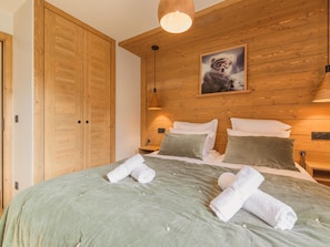 A wooden-paneled bedroom with a bed, pillows, and a painting on the wall.