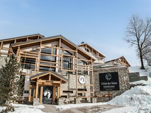 A modern hotel with a reception area, wooden exterior, stone walls, and a sign for 'L'éclat des Vénizies TERRÈRES'.