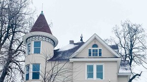 A large, two-story house with a distinctive tower and a circular window.