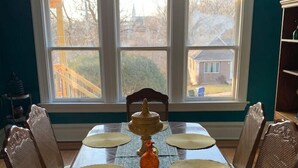 A dining table with a patterned tablecloth, surrounded by four chairs with cushioned seats.