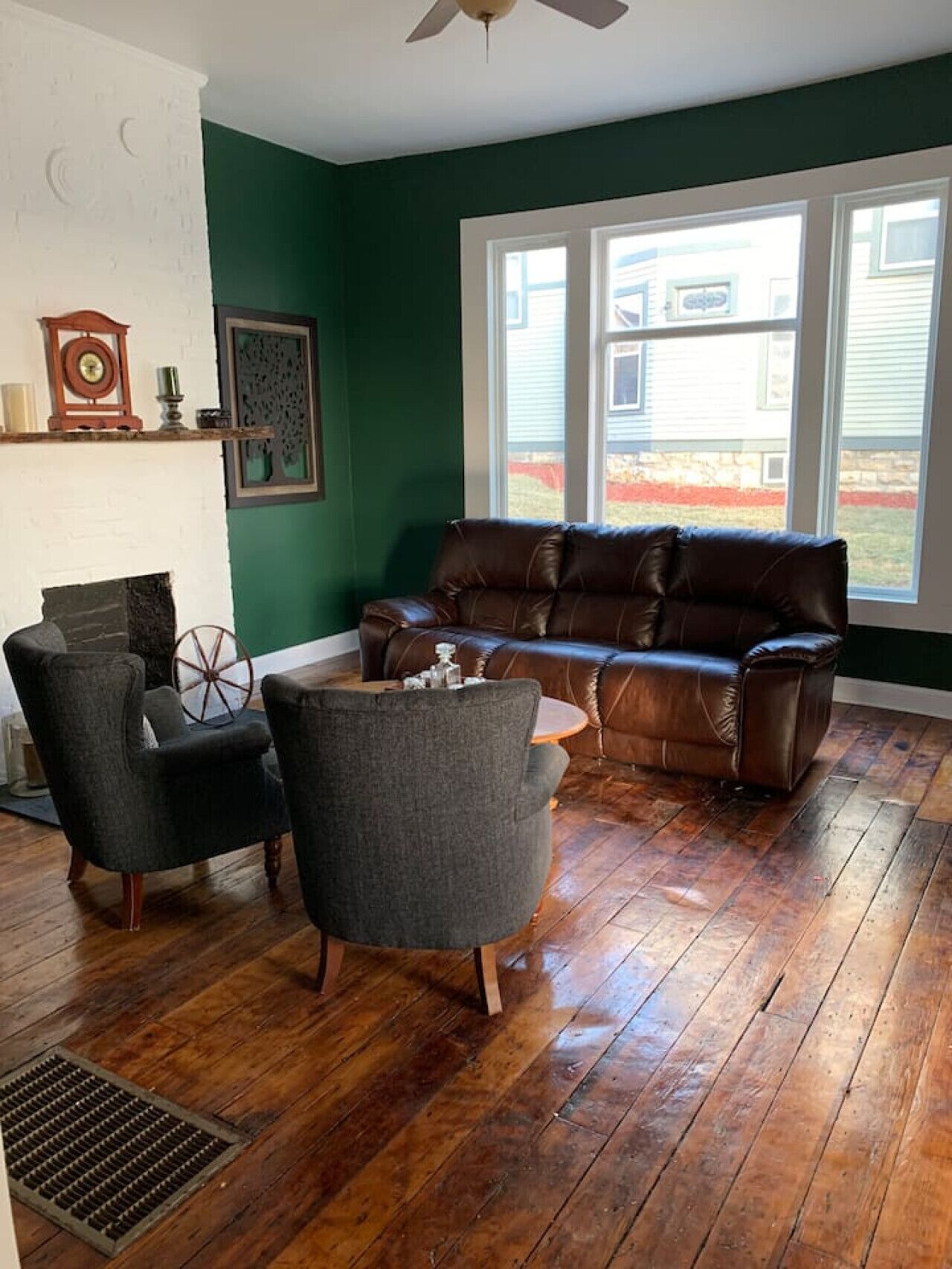 Ein Wohnzimmer mit braunem Ledersofa, zwei Sesseln, einem kleinen runden Tisch und einem Kamin.