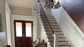 A grand staircase with a wooden finish and a white railing, leading to a second floor.