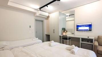 A hotel room with two beds, a desk, a chair, a TV, and a wardrobe.