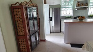 A kitchen with a central island, a cabinet with a decorative top, and a refrigerator. - Charming 3-bedroom bungalow with WiFi, AC in delightful Roseau (Roseau)