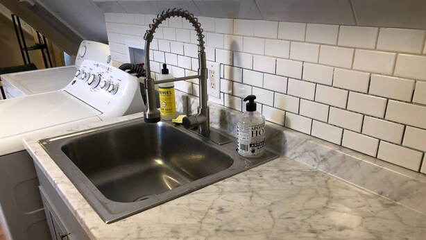 A kitchen with a stainless steel sink, a white stove, and a marble countertop. - Cozy Modern City Escape (Schenectady)