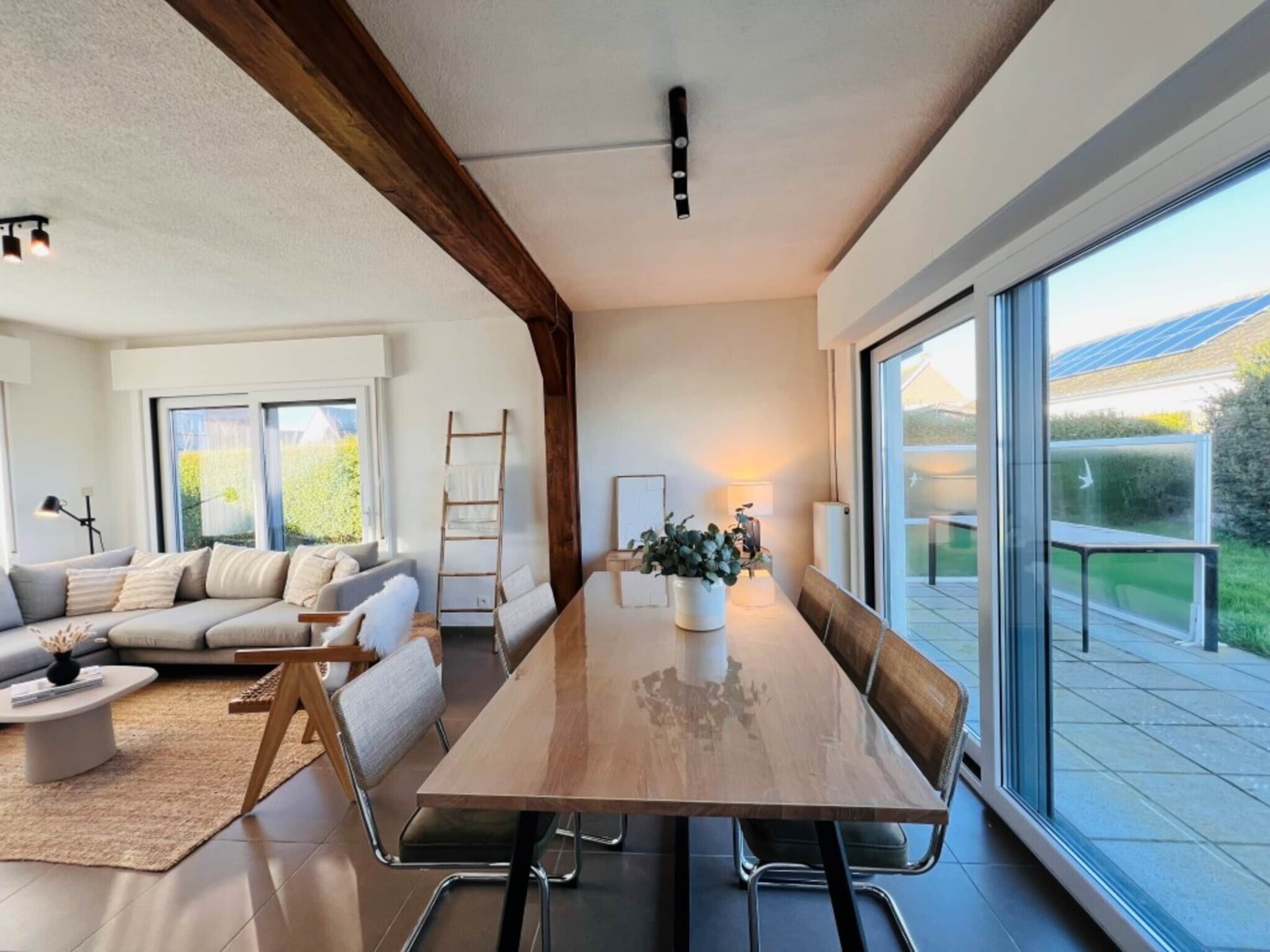 Una sala moderna con una mesa de comedor de madera, un sofá y una escalera.
