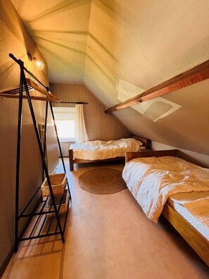 A small attic bedroom with two beds, a wooden loft bed, a hanging chair, and a large window. - Holiday Home in Wenduine Near Zeedijk (De Haan)