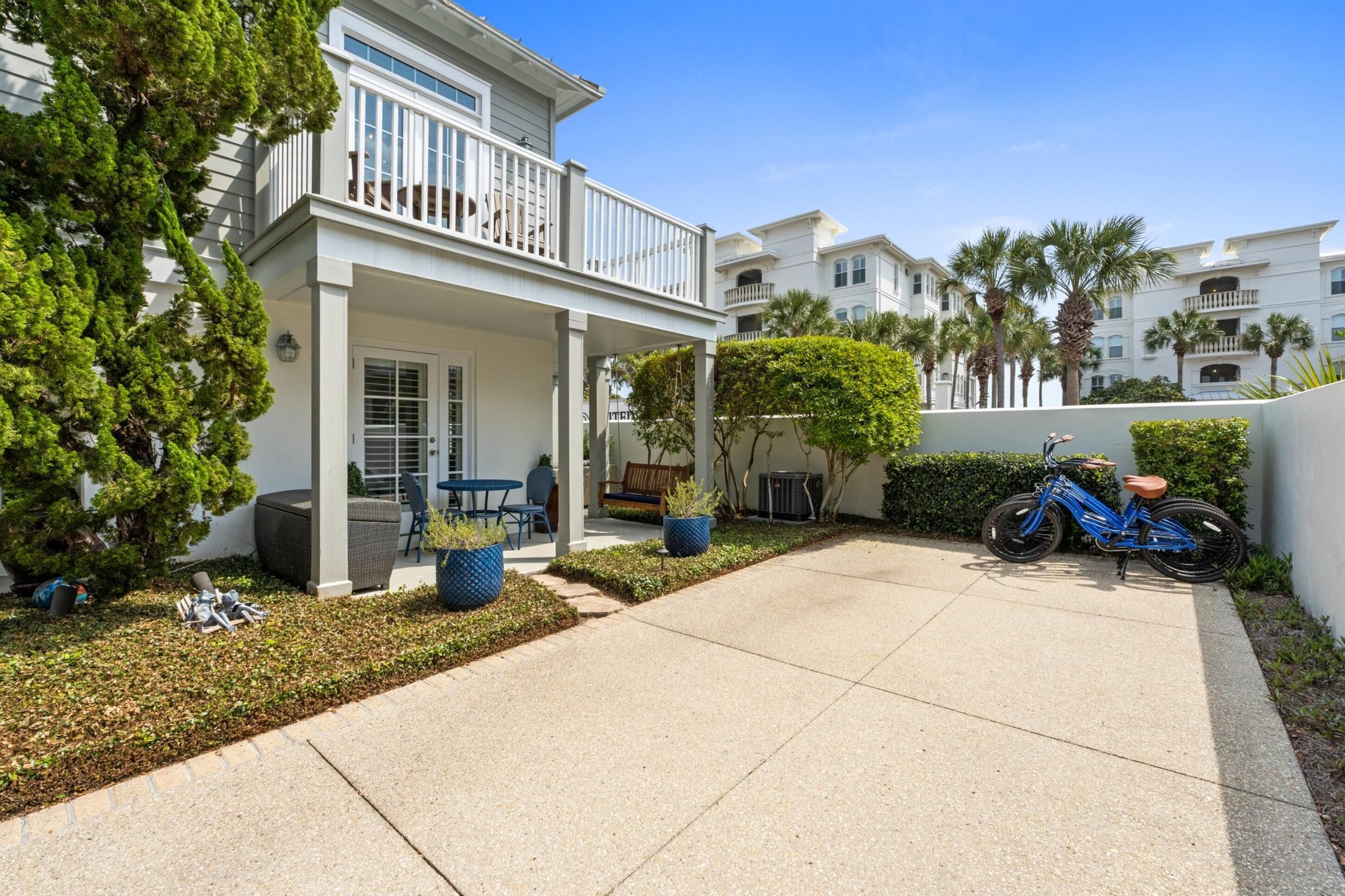 A residential building with a covered porch, outdoor seating, and a bicycle parked outside.