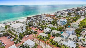 A coastal residential area with beachfront properties, a parking lot, and a clear view of the ocean. - 30A Sunset Beach House - Villa Infinity (Panama City Beach)