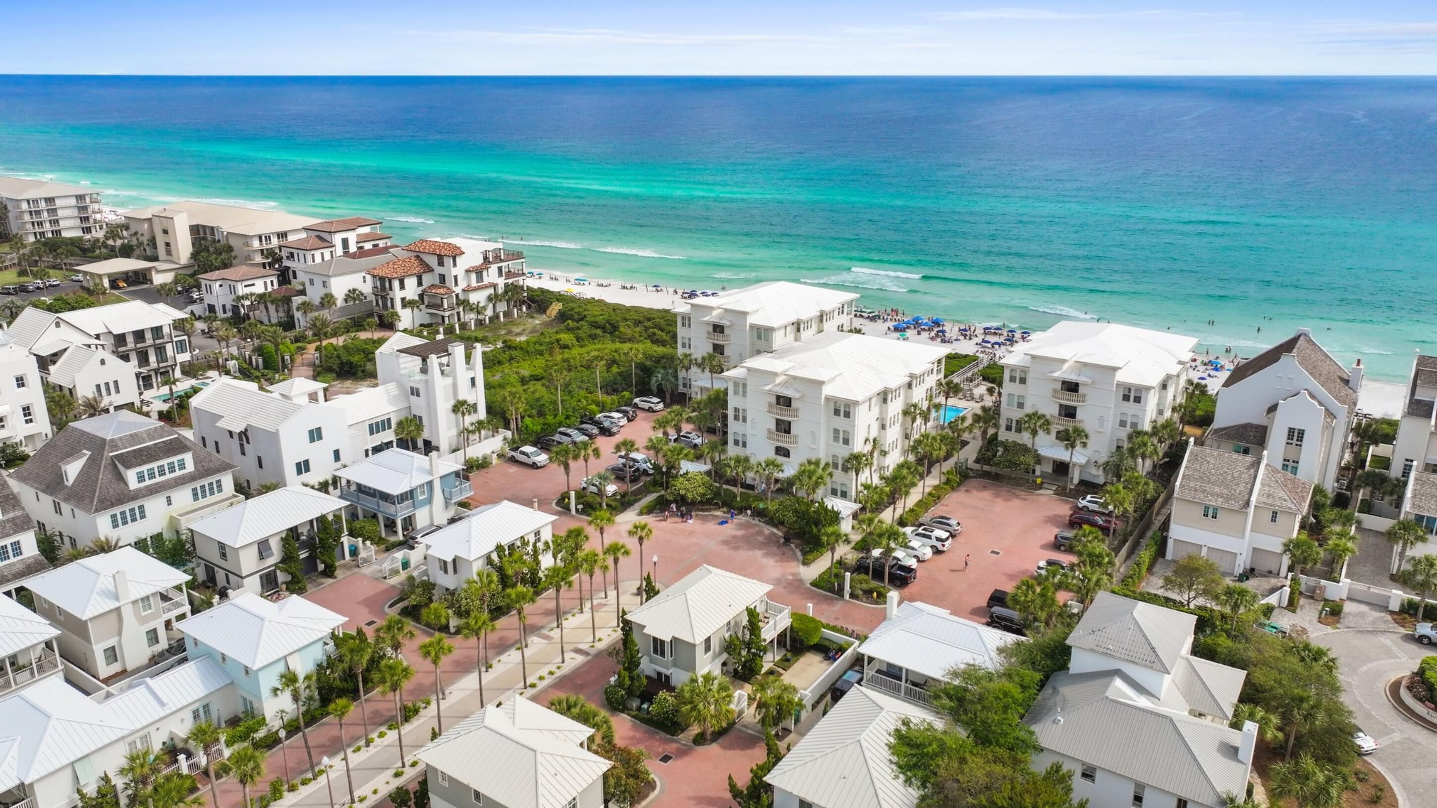 Zona residencial costera con edificios blancos, una playa y aguas azules cristalinas.