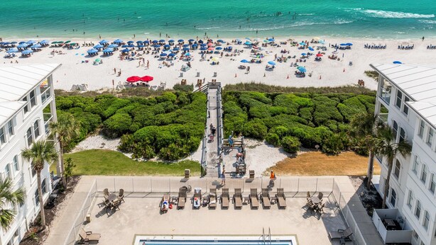 A beach resort with a pool area, beach umbrellas, and a view of the ocean. - 30A Sunset Beach House - Villa Infinity (Panama City Beach)