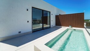 Un edificio moderno con piscina, grandes puertas correderas de vidrio y una cerca de madera.