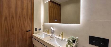 A modern bathroom with a double sink, wooden vanity, and a large mirror.