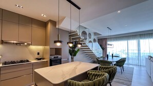 Una cocina moderna con una isla de mármol, electrodomésticos integrados e iluminación colgante.