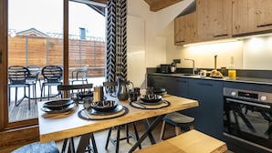 Une cuisine moderne avec des meubles en bois, un grand îlot central doté d’un évier et un coin repas avec des chaises et une table.