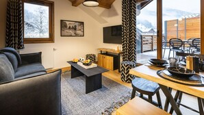 Un intérieur moderne avec un canapé, une table à manger et un téléviseur fixé au mur.