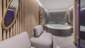 A modern bathroom with a freestanding bathtub, a large mirror, and a cushioned seating area. - Apartment in Plan Peisey Near Vanoise Park (Peisey-Nancroix)