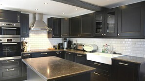 A modern kitchen with dark cabinetry, stainless steel appliances, and a central island. - Villa in Stavelot With Lake View and Jacuzzi (Stavelot)