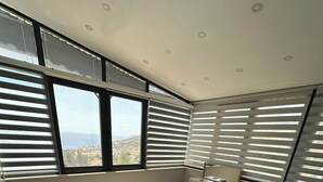 Un dormitorio moderno con una cama grande, una mesita de noche y vistas al mar a través de las ventanas.