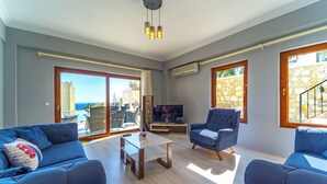 Amplia sala de estar con televisor grande, asientos cómodos y un balcón con vistas.