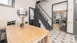 A modern kitchen with a wooden table, a staircase, and a view of the living area.