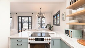 A modern kitchen with a large stove, oven, and microwave, white marble countertops, and light blue cabinets.