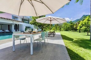 Relax by the pool surrounded by lush greenery and distant mountains.