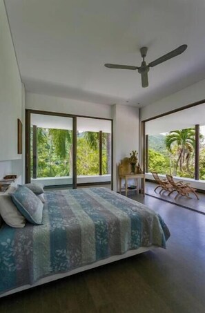 Relax in this serene bedroom with a large bed, ceiling fan, and comfortable seating area.