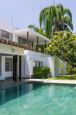 Enjoy a refreshing dip in the pool surrounded by lush greenery and palm trees.