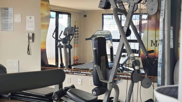 A gym with exercise equipment, a treadmill, and a mirror reflecting the room.
